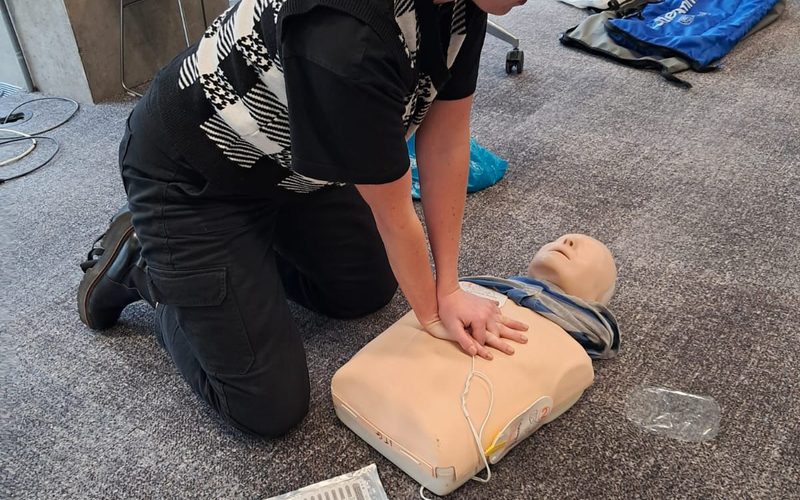 Staff member practising pad placement on an AED trainer unit